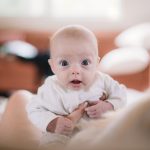 A wide eyed baby looks into the camera